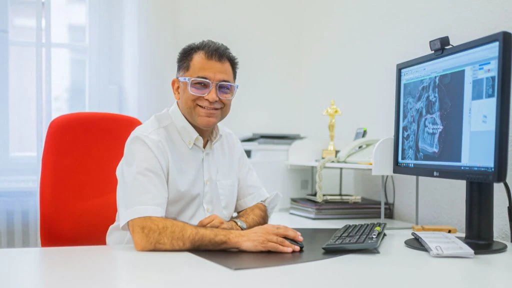 Dr. Ali Sohani sitz an seinem Schreibtisch in seiner kiefernorthopädischen Praxis in Heidelberg