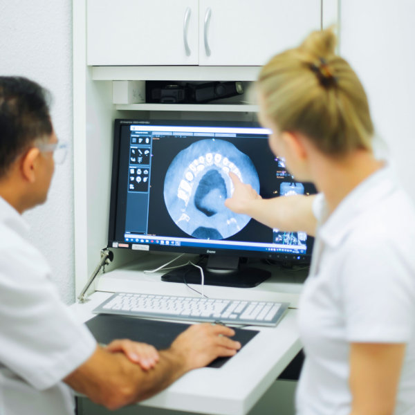 Kiefernorthopäde Dr. Sohani und Zahnärztin Dr. Vivien Knetsch betrachten eine Röntgenaufnahme eines Gebisses